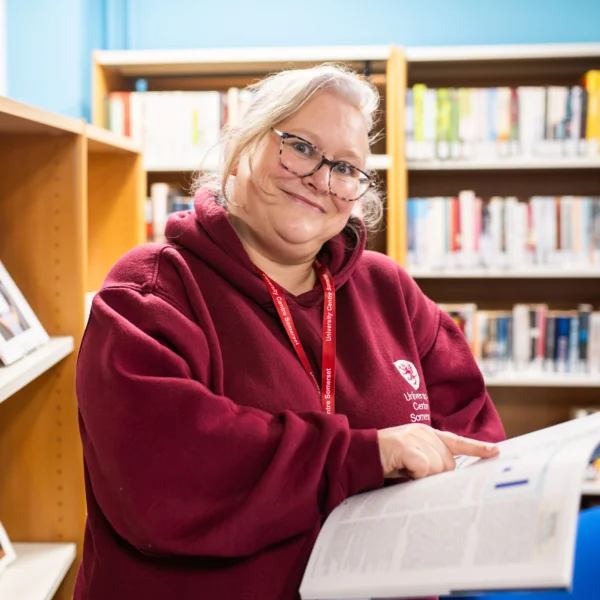 Woman holding papers in a library setting.