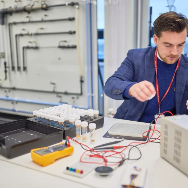 man in a blue suit working on electronics with various tools and equipment.