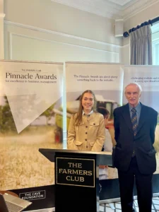 Man and woman standing behind a podium with a sign that reads 'The Farmers Club', at the Pinnacle Awards in London
