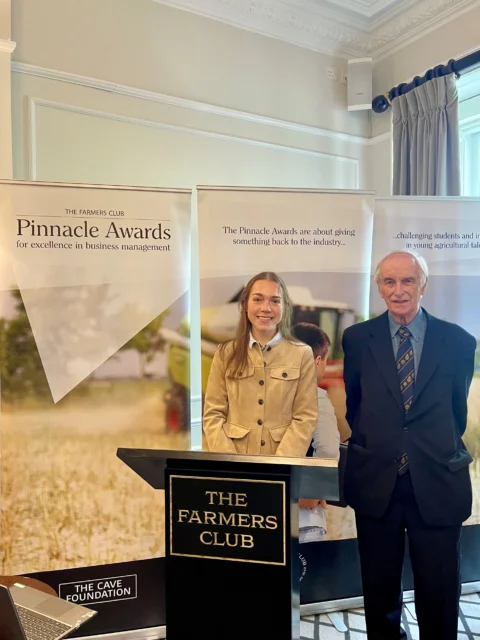 Man and woman standing behind a podium with a sign that reads 'The Farmers Club', at the Pinnacle Awards in London
