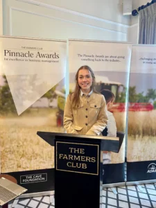A woman standing behind a lectern with a sign that reads The Farmers Club at the Pinnacle Awards final
