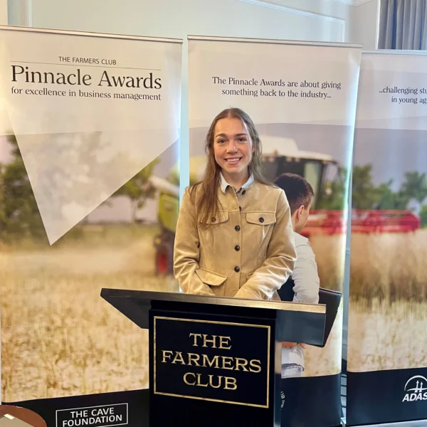 A woman standing behind a lectern with a sign that reads The Farmers Club at the Pinnacle Awards final