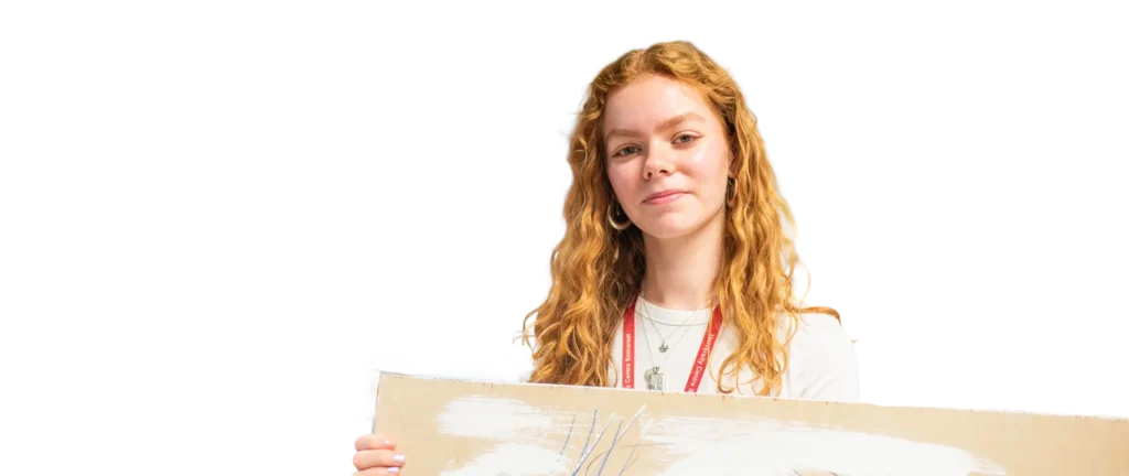 A woman with long red hair smiling behind a cardboard box