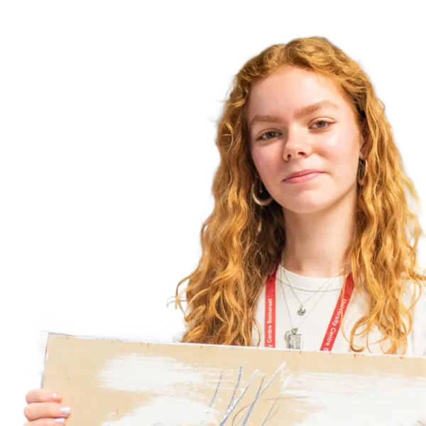 A woman with long red hair smiling behind a cardboard box