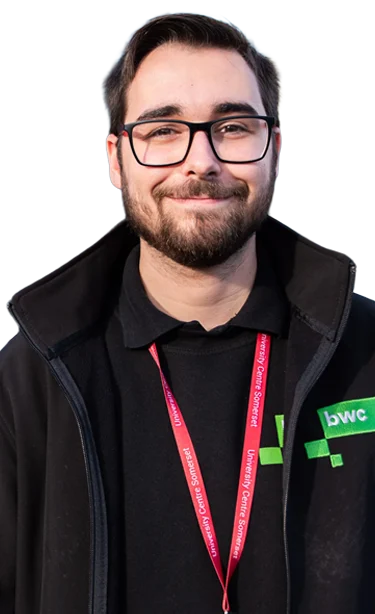 Man with glasses and a lanyard around his neck, wearing a black jacket with a green logo.