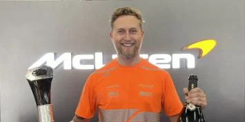 Man in orange shirt holding trophy and champagne bottle