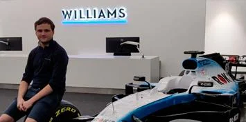 Man sitting next to a Williams F1 car