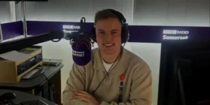 A man wearing headphones sitting next to a microphone in a radio studio.