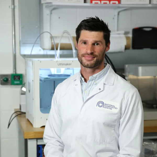A male doctor smiling in a medical setting, wearing a white lab coat.
