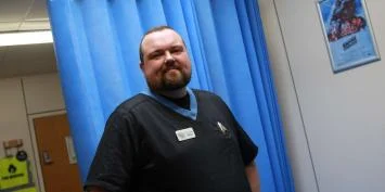 a man wearing a black shirt and blue lanyard