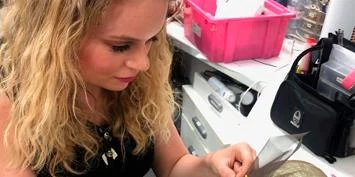 A woman with long blonde hair is looking down at something she is holding in her hand.