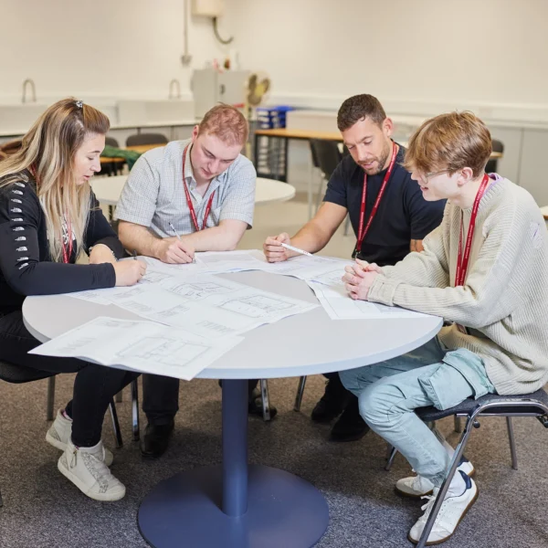 Four students sitting around a table looking at papers