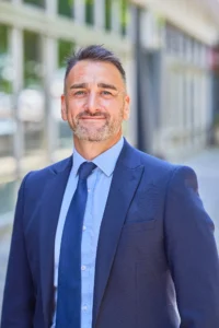 Professional man in a blue suit standing outside a modern building.