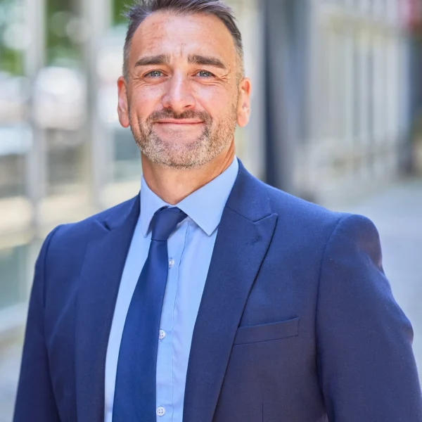 Professional man in a blue suit standing outside a modern building.