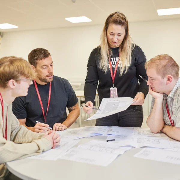 Four people collaborating on a project, sitting around a table with papers and documents.