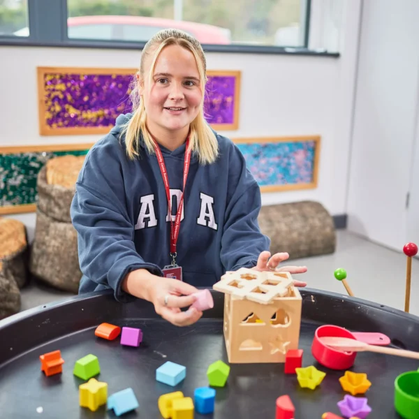 A young girl playing with wooden blocks and toys on a table.