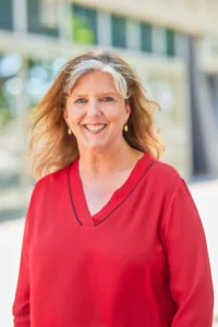 Smiling woman with blonde hair wearing a red top.