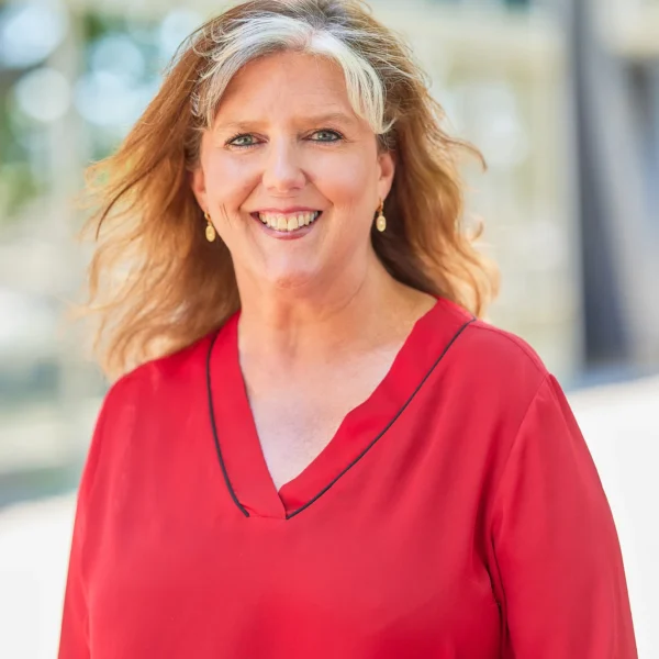 Smiling woman with blonde hair wearing a red top.