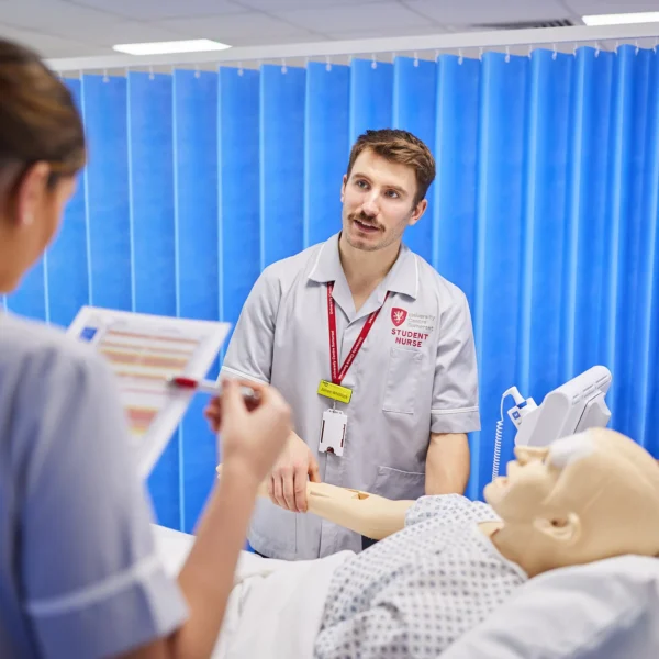 Medical students practice on a mannequin.