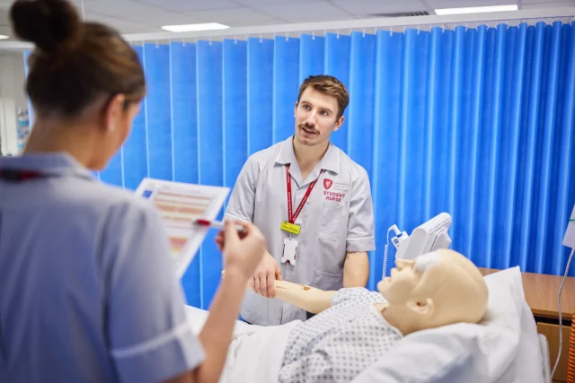 Medical students practice on a mannequin.
