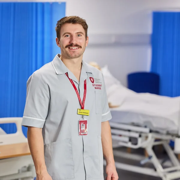 A man in a hospital setting wearing a light grey uniform.