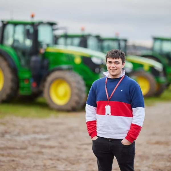 Young man standing in front of tractors