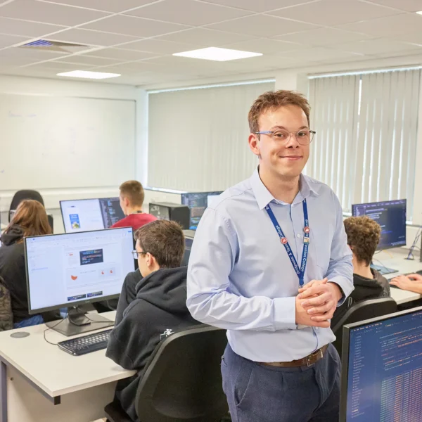 A man standing in a classroom with students using computers.