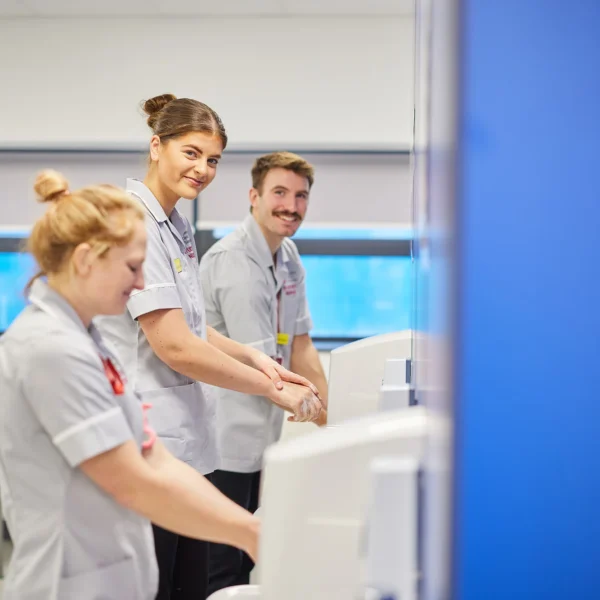 Three medical professionals interacting with a computer screen.