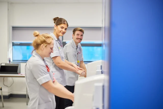 Three medical professionals interacting with a computer screen.