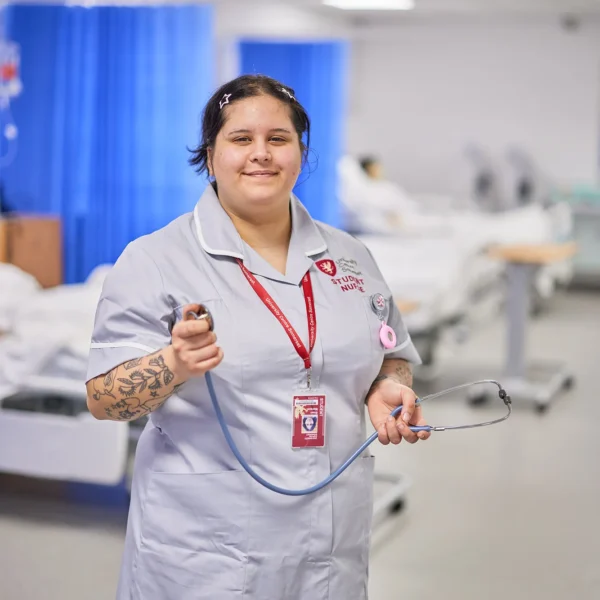 A female nurse in a hospital setting, holding a stethoscope.