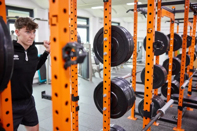 Man in a gym preparing to exercise with a squat rack.