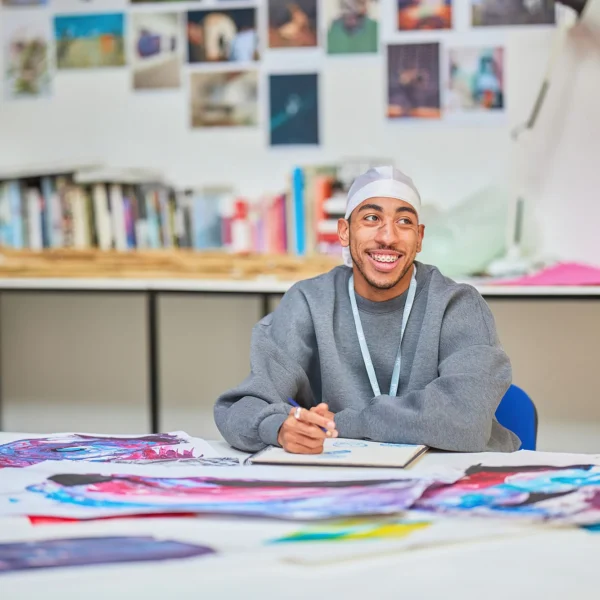a man sitting at a desk with art supplies