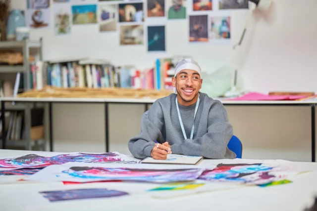 a man sitting at a desk with art supplies
