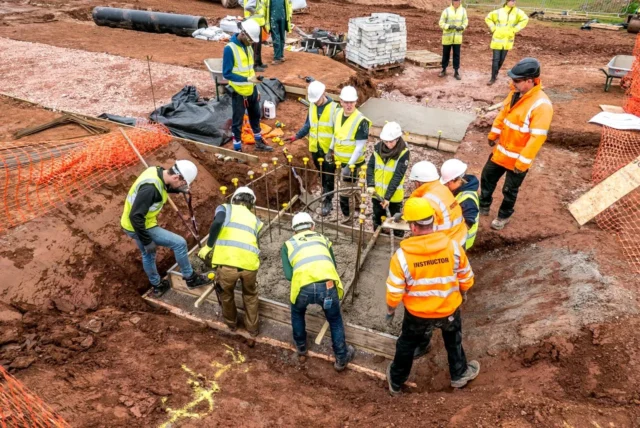 Construction workers in safety gear building a foundation