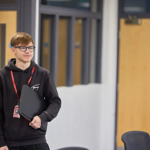 Teenager holding a laptop in a room with wooden doors.