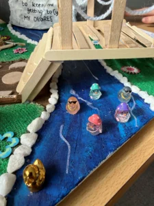 A child's hands on a craft bridge over water with jellyfish and sea creatures.