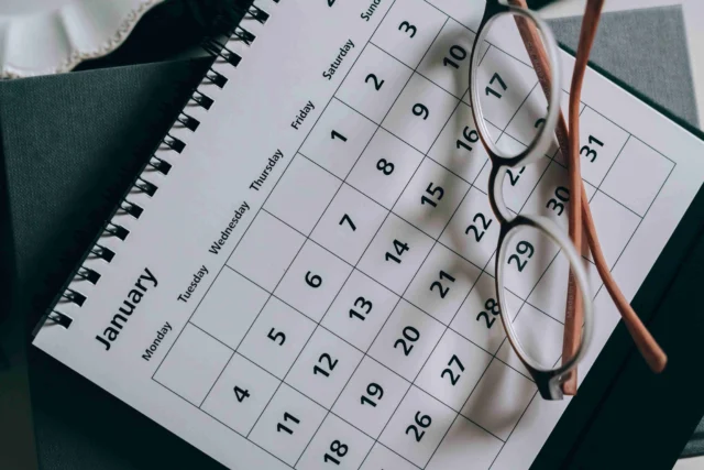 January calendar and glasses on a dark surface