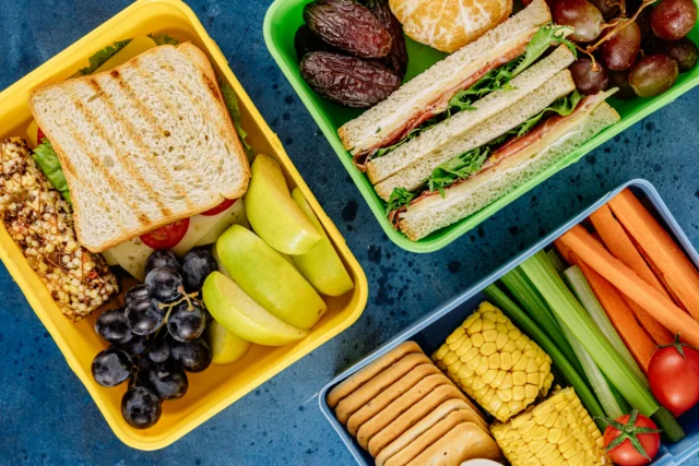 Three lunchboxes filled with various food