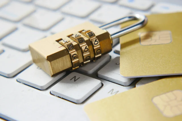 A combination padlock with a credit card on a keyboard, symbolizing online security and protection of sensitive financial information.