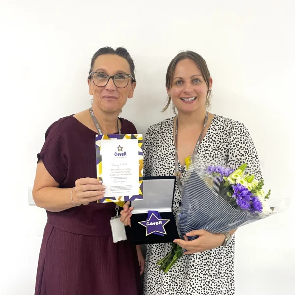 UCS Deputy Head of Nursing and Health Professions, Maria Santrian, presenting Emily White with her Cavell Star Award and a bouquet of flowers. Both are smiling at the camera.