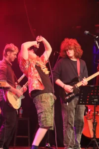 A musician plays guitar on stage with a band.