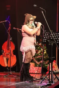 A singer on stage with a microphone and a cello