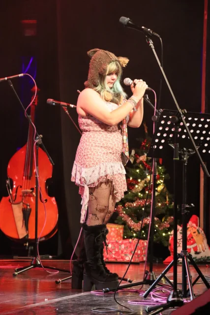 A singer on stage with a microphone and a cello