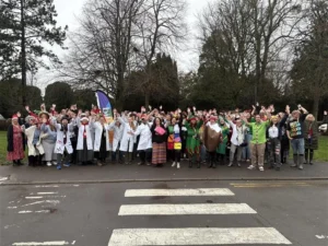 A large group of people of various ages gathered on a road, waving their arms.