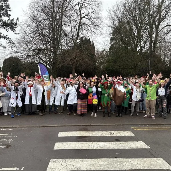 A large group of people of various ages gathered on a road, waving their arms.