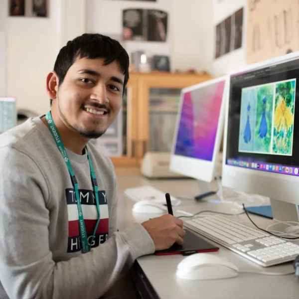Man sitting at a desk with two computer monitors.
