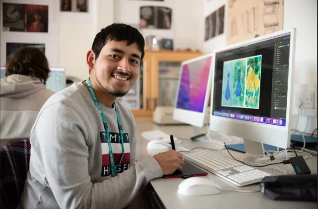 Man sitting at a desk with two computer monitors.