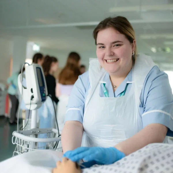 Nurse trainee practicing on a mannequin patient in a simulated hospital environment