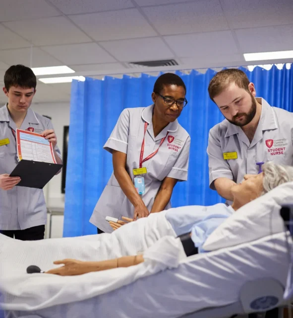 Medical students observing a simulation on a patient.