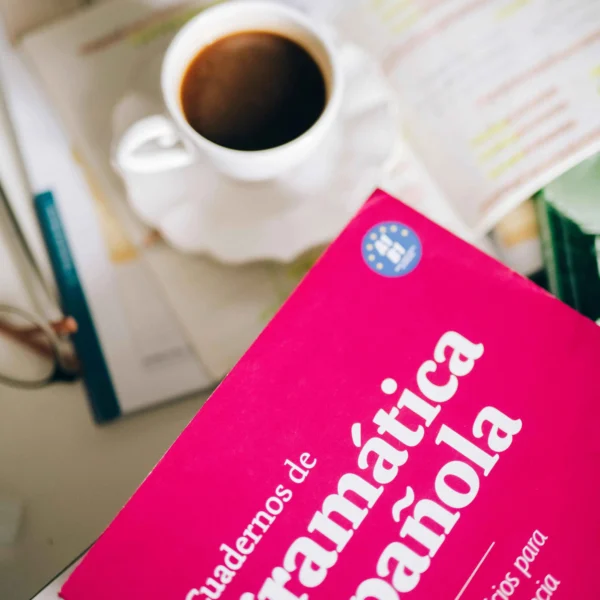 A Spanish grammar workbook with a cup of coffee on a desk.